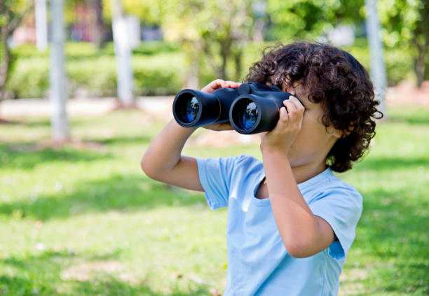 istock Little boy holding a binocular at park 1094360122
