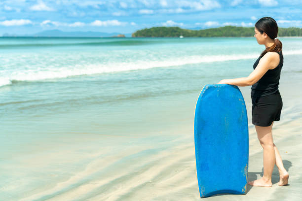 Asian woman hold surfboard on the beach