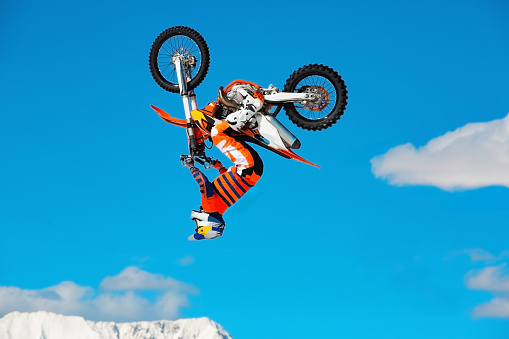 Corredor en moto participa en Cross motocross en vuelo, Salta y saca en trampolín contra el cielo. Descanso extremo activo del concepto. photo