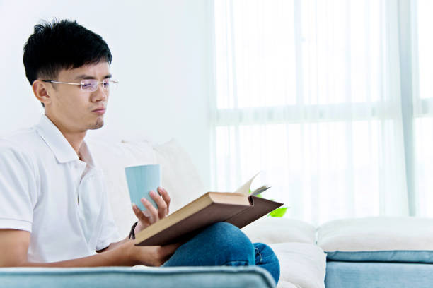 istock Young asian man drinking coffee and reading book 1094363206