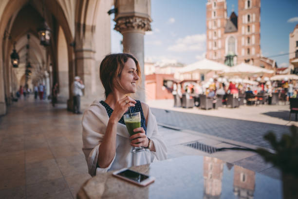 Tourist woman exploring Europe Relaxed woman at cafe drinking green smoothie and enjoying the old town of Krakow krakow photos stock pictures, royalty-free photos & images