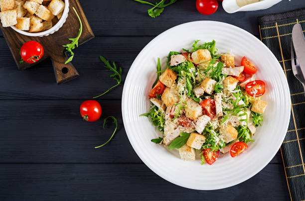 Healthy grilled chicken Caesar salad with tomatoes, cheese and croutons. North American cuisine. Top view stock photo