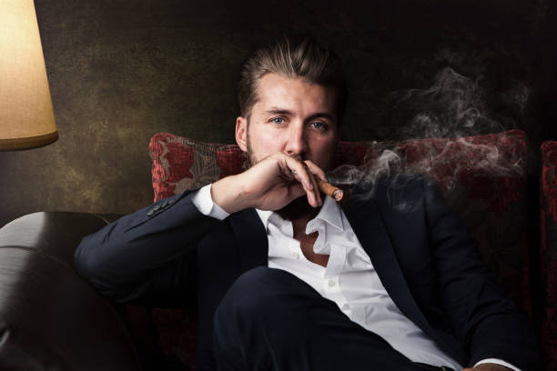 Attractive business man with a cigar is relaxing on the couch Attractive business man with a cigar is relaxing on the couch sex symbol stock pictures, royalty-free photos & images