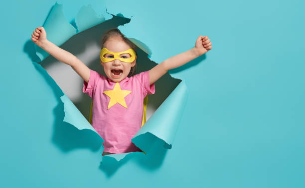 child playing superhero Little child playing superhero. Kid on the background of bright blue wall. Girl power concept. Yellow, pink and  turquoise colors. heroes photos stock pictures, royalty-free photos & images