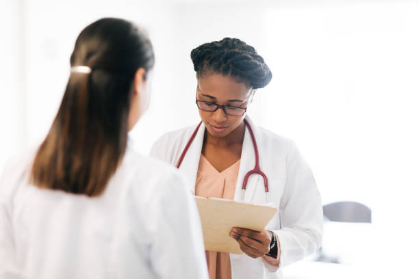 istock Two female doctors standing face to face and looking at clipboard 1094389338