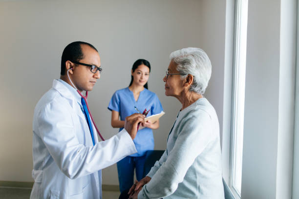 male doctor consulting senior patient and nurse taking notes - healthcare and medicine nurse doctor general practitioner imagens e fotografias de stock