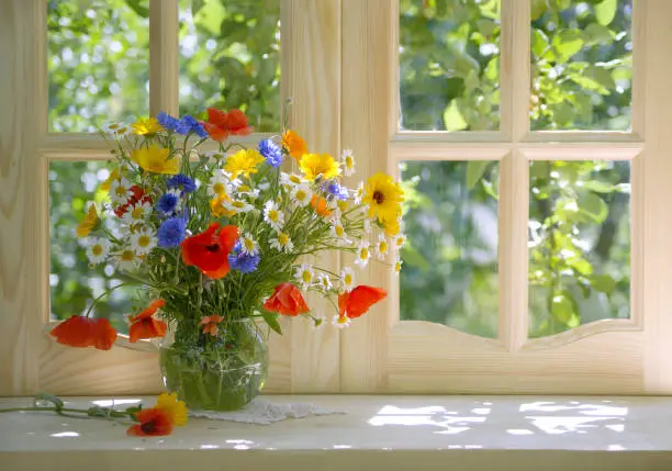 Photo of still life with a bright summer bouquet on a sunlit windowsill