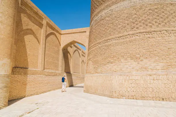 Back view of senior women walking by The Kalyan minaret on right side to the to the Poi Kalyan square in Bukhara, which is UNESCO World Heritage Site in Bukhara, Uzbekistan.