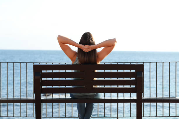 istock Woman relaxing on the beach sitting on a bench 1094391576