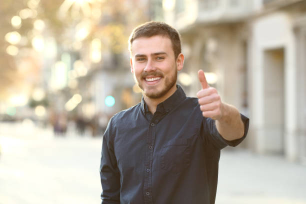 happy man in the street gesturing thumbs up - congratulating winning agreement thumbs up imagens e fotografias de stock