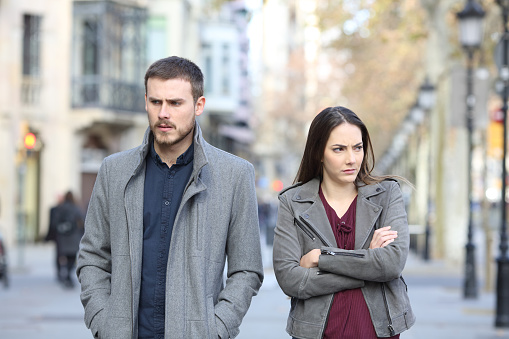 Angry couple walking in the street after argument