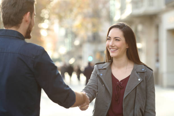 glücklich mann und frau handshaking in einer stadtstraße - greeting teenager handshake men stock-fotos und bilder