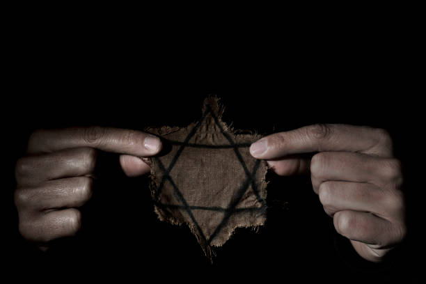man with a ragged Jewish badge closeup of a ragged Jewish badge in the hands of a man, with a dramatic effect concentration camp photos stock pictures, royalty-free photos & images