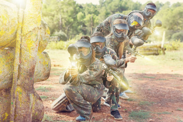 Paintball team running with marker guns Expressive paintball team running with marker guns at the open playing field paintballing stock pictures, royalty-free photos & images