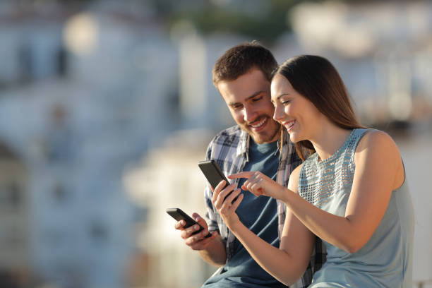 istock Happy couple sharing phone content in a town 1094401492