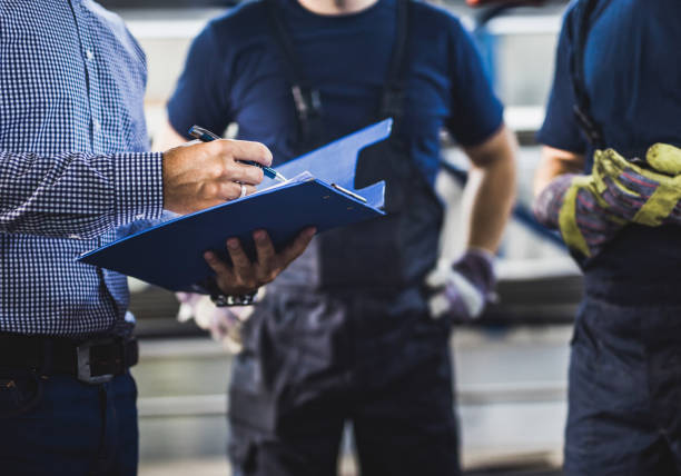 unrecognizable foreman going through paperwork with manual workers in a warehouse. - foreman imagens e fotografias de stock