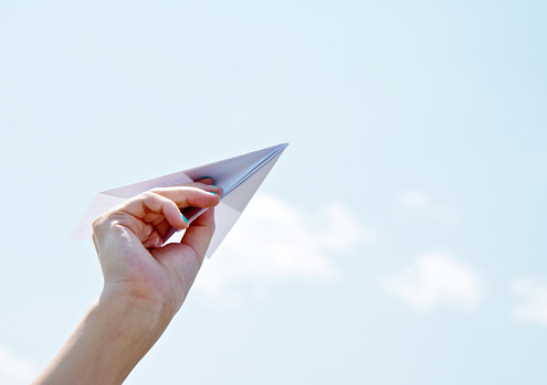 Hand holding a paper plane ready to fly