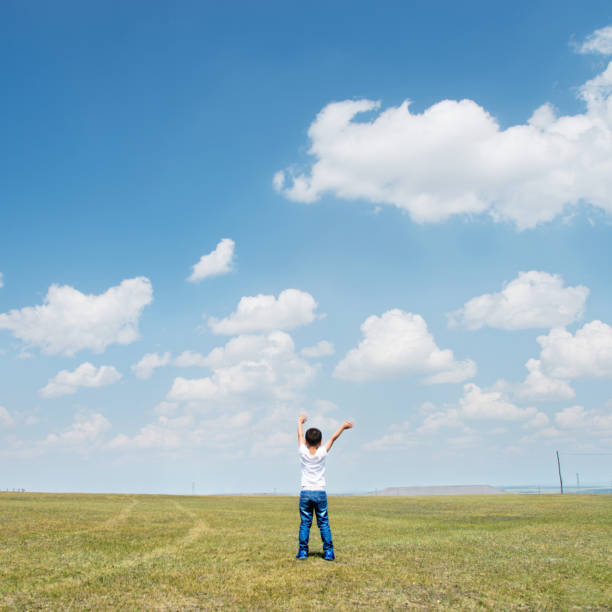istock Little boy arms raised under blue sky 1094409214