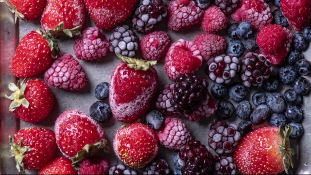Top view variety of forest fruits, berries freezing, time lapse