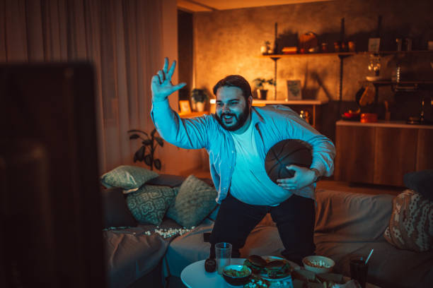 istock Fat man watching basketball match 1094421006