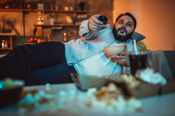 istock Fat man eating popcorn 1094421104