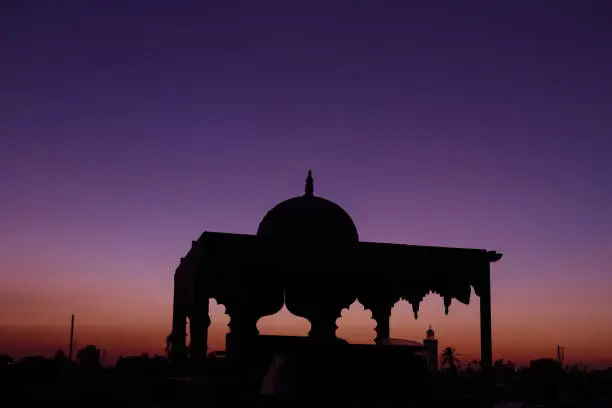 Beautiful sunset in Marrakech, Morocco. Silhouette of oriental architecture in front of colorful purple creamy sky