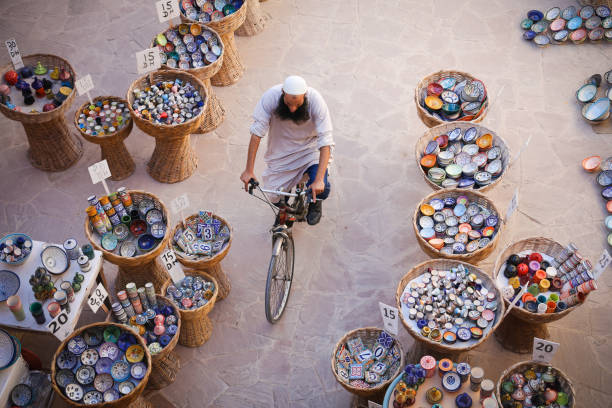essaouira, marokko - 2. oktober 2018: lokalen muslimischen mann reiten fahrrad durch traditionelle marokkanische keramik strassenlokal in der einkaufsstraße von essaouira medina (altstadt) - ouarzazate stock-fotos und bilder