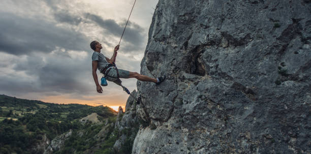 Disability man free climbing on rock mountain One man, disability young man with prosthetic leg free climbing on a rock mountain in nature.. disabled person hiking outdoors stock pictures, royalty-free photos & images