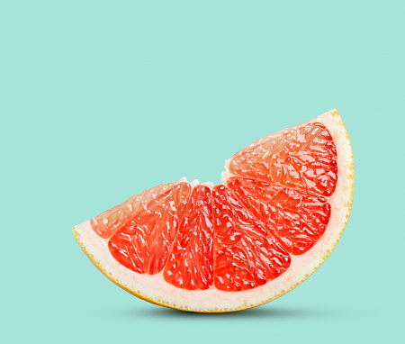 Perfect red grapefruit slice on pastel green. This file is cleaned, retouched and contains clipping path.
