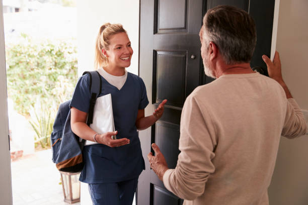 Senior man opening his front door to a female healthcare worker making a home health visit Senior man opening his front door to a female healthcare worker making a home health visit returning home from work stock pictures, royalty-free photos & images