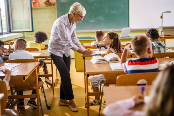istock Happy senior teacher talking to elementary student in the classroom. 1094436086
