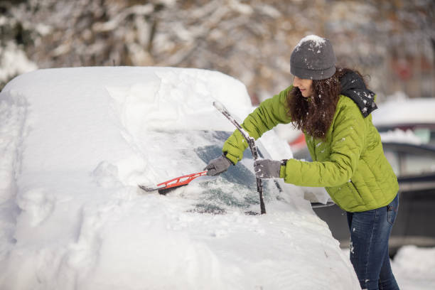 donna che pulisce la sua auto dalla neve - snow cleaning foto e immagini stock