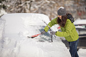 Woman cleaning her car from snow