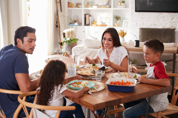 istock Young Hispanic family sitting at dining table eating dinner together 1094438408