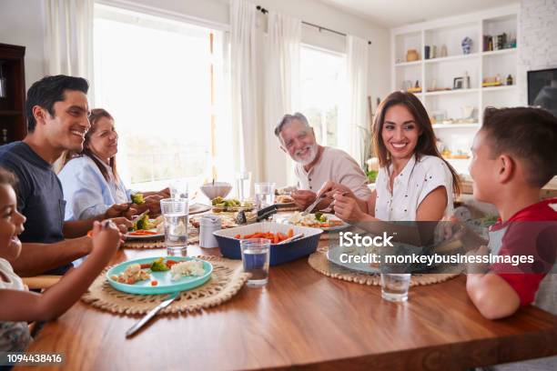 Three Generation Hispanic Family Sitting At The Table Eating Dinner Stock Photo - Download Image Now