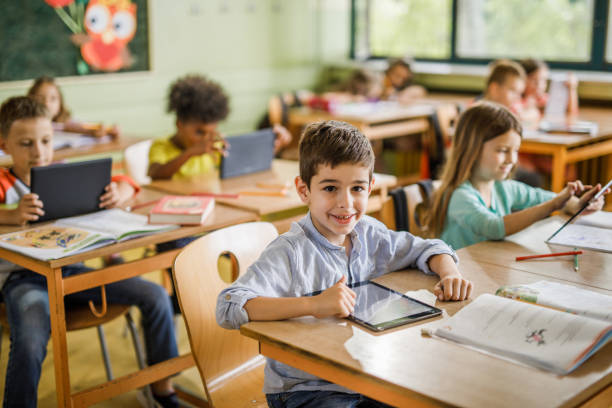 istock Happy schoolboy e-learning over digital tablet in the classroom. 1094439832
