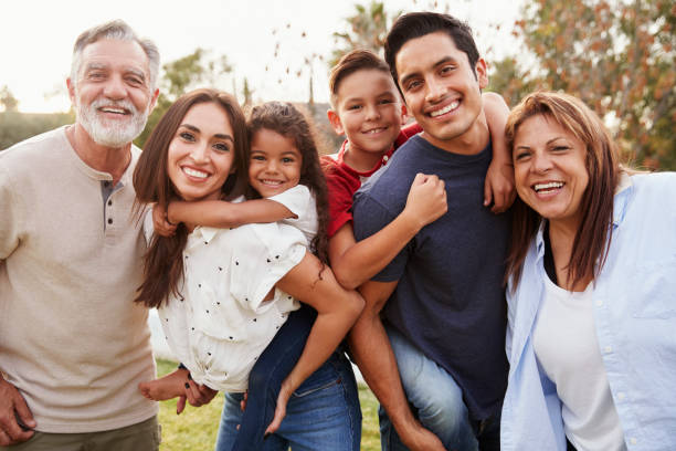 Three generation Hispanic family standing in the park, smiling to camera, selective focus Three generation Hispanic family standing in the park, smiling to camera, selective focus hispanic family stock pictures, royalty-free photos & images