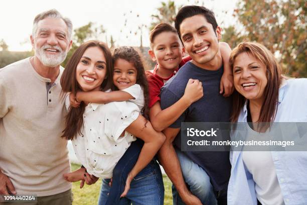Three Generation Hispanic Family Standing In The Park Smiling To Camera Selective Focus Stock Photo - Download Image Now