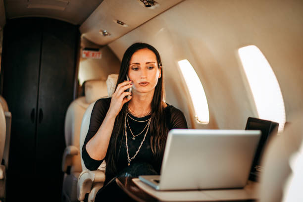 istock Beautiful rich woman working on a laptop and talking on a smart phone at the same time while flying on a private jet 1094440582