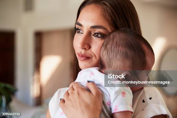 Millennial Hispanic Mother Holding Her Newborn Son Close To Her Chest Head And Shoulders Close Up Stock Photo - Download Image Now