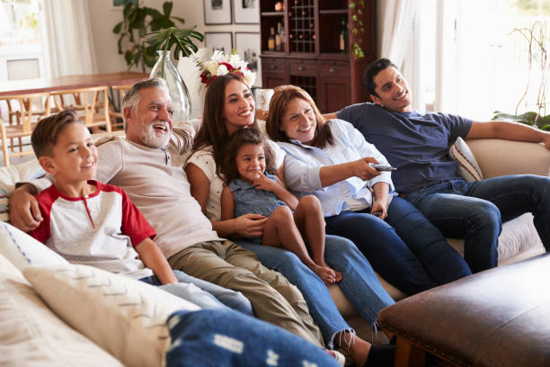 istock Three generation Hispanic family sitting on the sofa watching TV, grandmother using remote control 1094443232