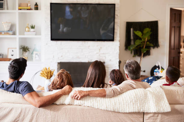 vista posteriore della famiglia ispanica di tre generazioni seduta sul divano a guardare la tv - guardare la tv foto e immagini stock