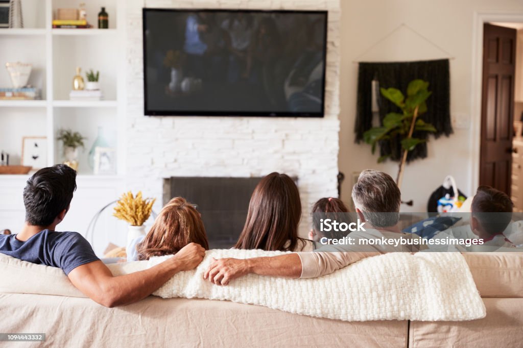 Back view of three generation Hispanic family sitting on the sofa watching TV Watching TV Stock Photo