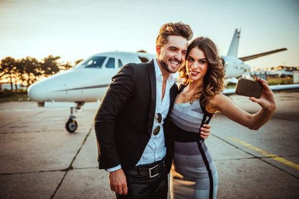 istock Rich and famous couple taking a selfie for social media while embracing each other in front of a private airplane parked on a tarmac 1094443380