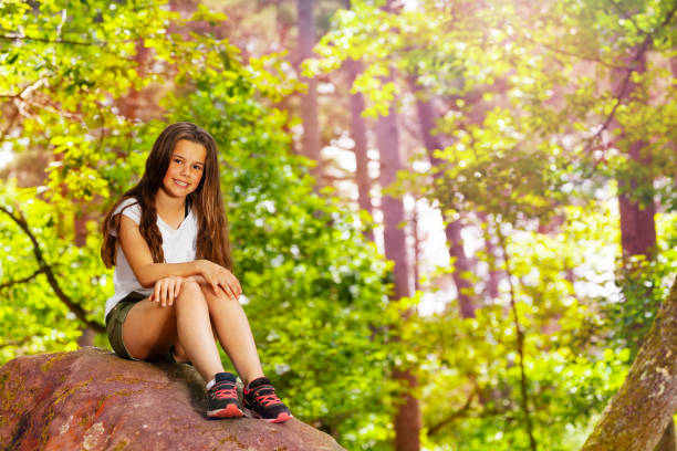 istock Little girl sit on stone in the forest 1094443510