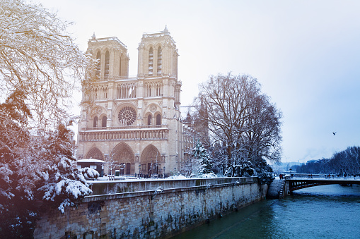 Winter view of Seine river embankment and Notre-Dame Cathedral in snow, Paris