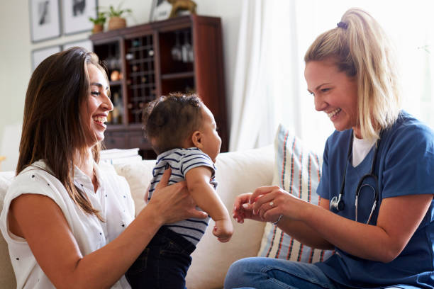 trabajadora de salud a una joven madre y su hijo en casa - women mother baby happiness fotografías e imágenes de stock