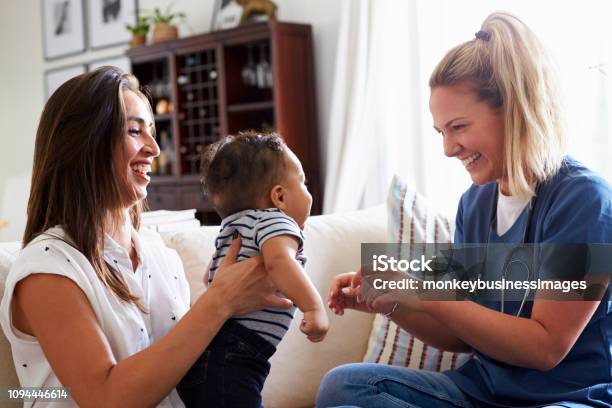 Female Healthcare Worker Visiting A Young Mum And Her Infant Son At Home Stock Photo - Download Image Now