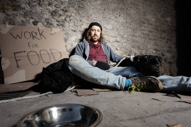 istock Man in dirty rags hugging dog sitting on sidewalk 1094446832