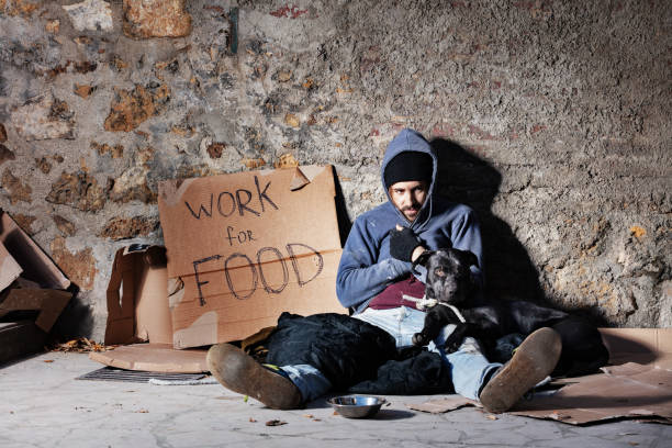 istock Jobless man with dog, sitting next to alms bowl 1094446854
